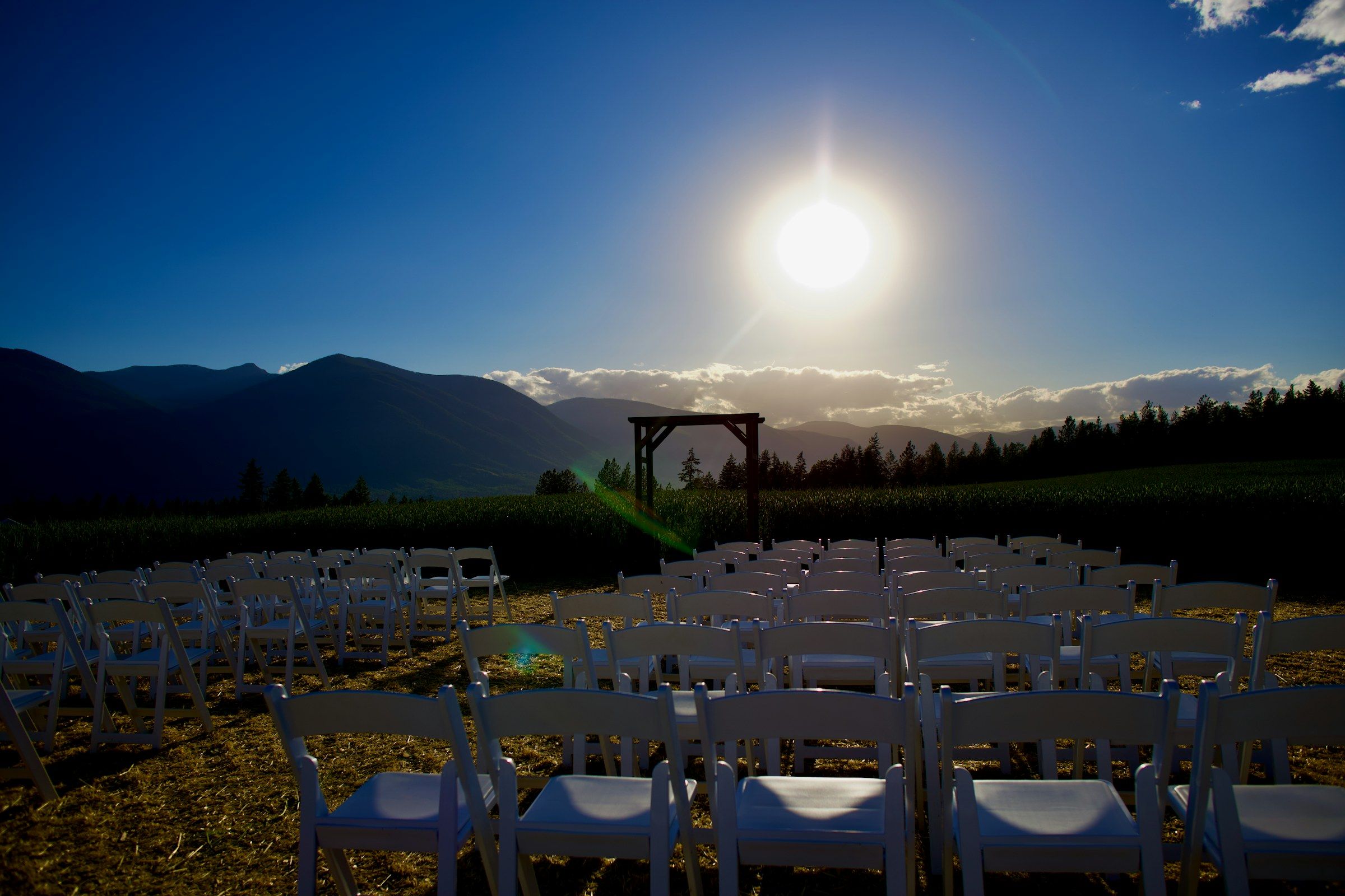 Rows of white chairs set for an outdoor ceremony facing the mountains