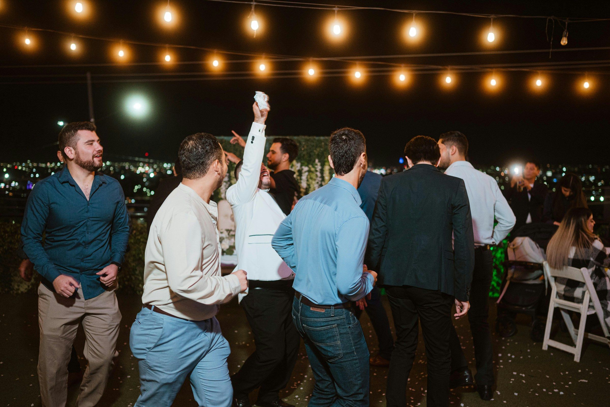 Guests dancing under festoon lights at a night reception