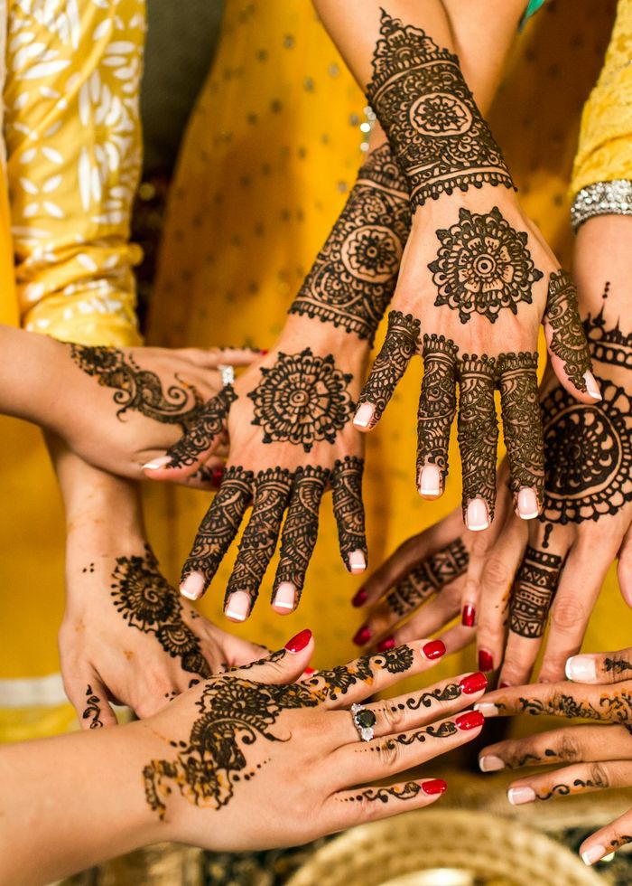 Hands decorated with intricate henna, held together in a circle