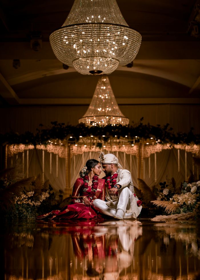 Newlyweds seated together under chandeliers at their reception
