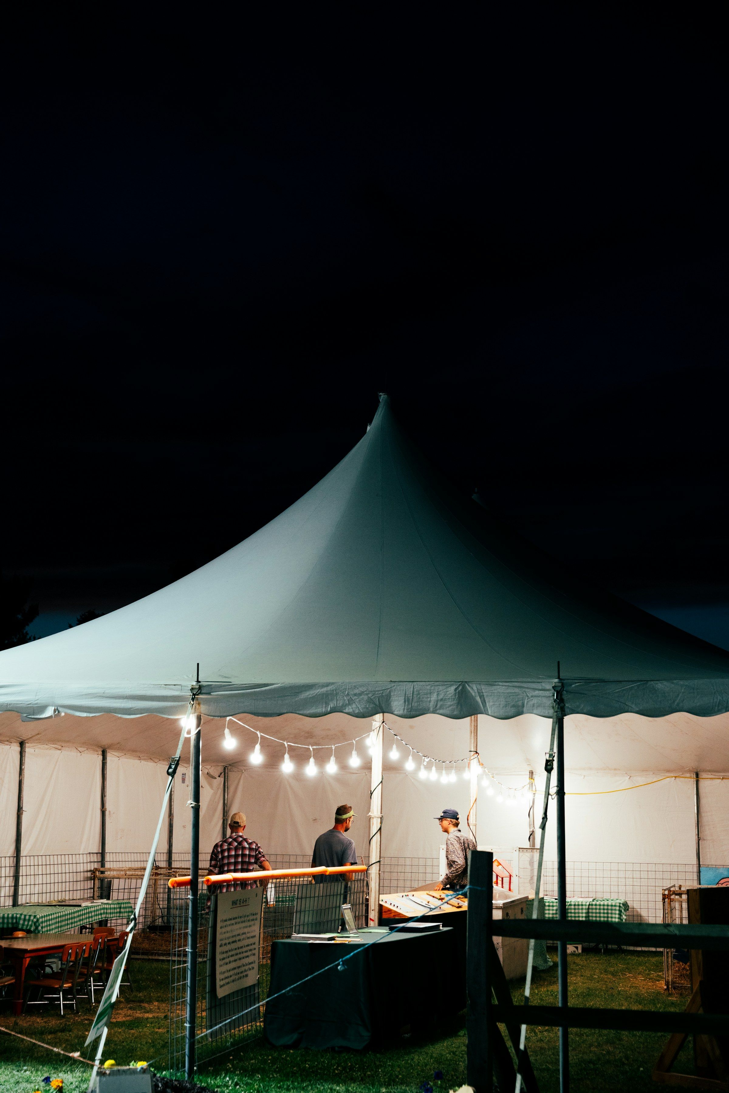 A white peaked tent glowing with string lights at night